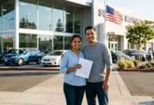New immigrant couple holding car insurance documents outside US dealership